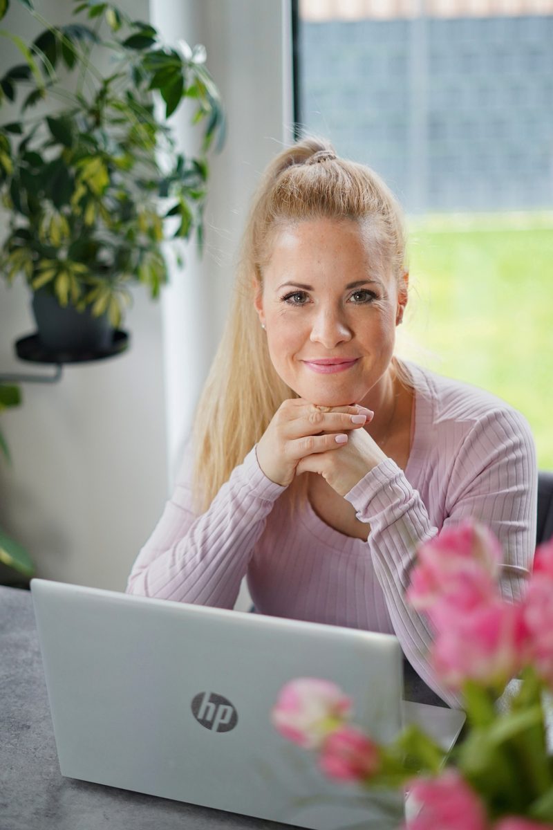 Josephine Fröhlich, Psychologin und Resilienztrainerin, sitzt lächelnd an ihrem Laptop